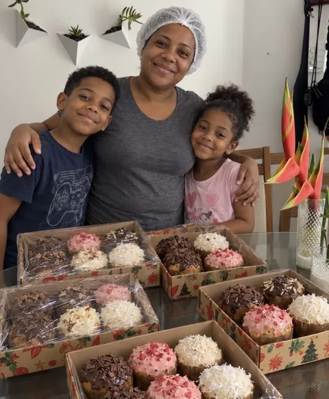 Mãe com dois filhos e caixas de mini panetones caseiros